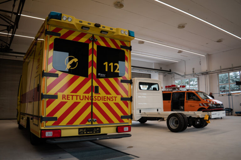 Heckansicht eines gelben Rettungswagens mit Notrufnummer 112 in der Werkstatthalle
