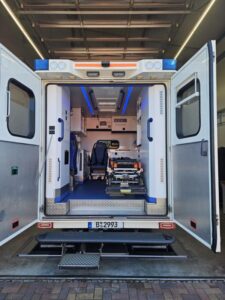 Blick durch die geöffneten Hecktüren in den Patientenraum eines Rettungswagens mit Fahrtrage und Ladelift